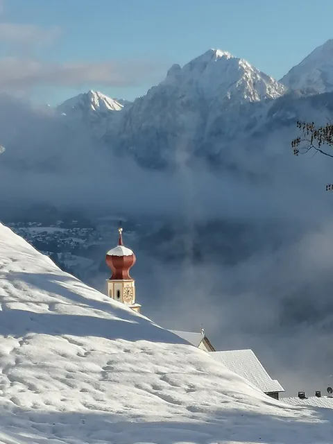 Campanile davanti alle Dolomiti innevate